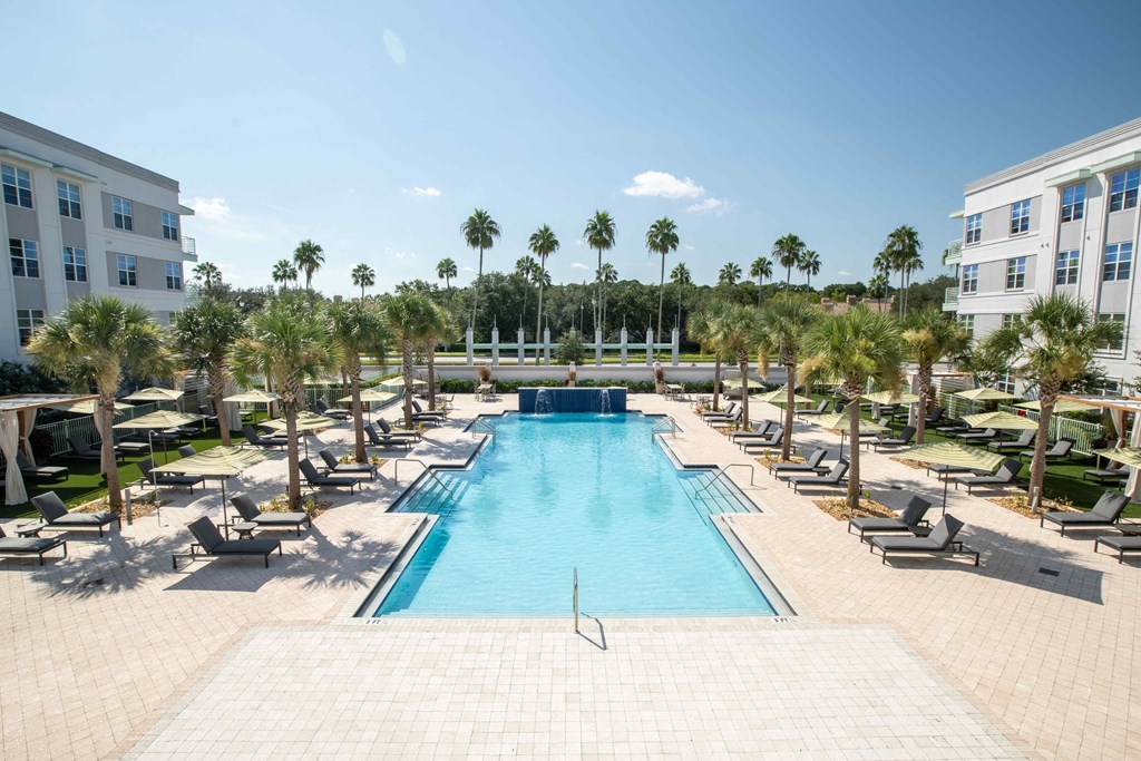 a swimming pool with chaise lounge chairs and palm trees in the background at Delamarre at Celebration, Celebration