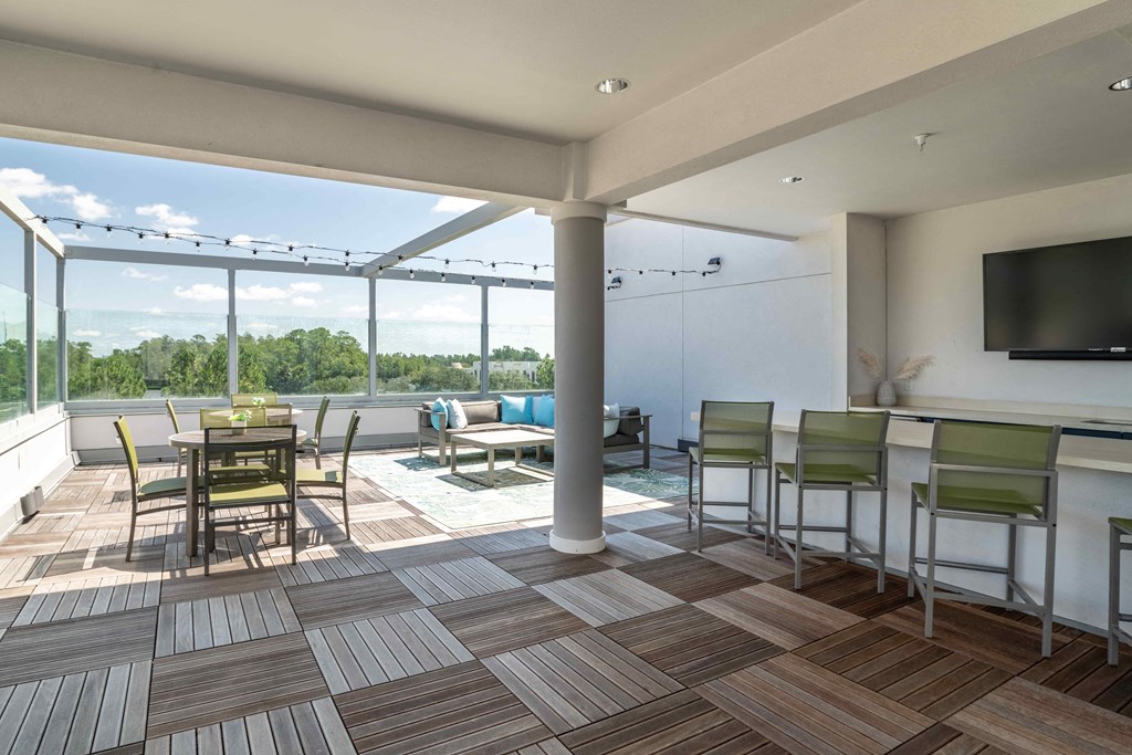 a patio area with a dining table and chairs and a flat screen tv at Delamarre at Celebration, Celebration