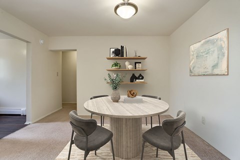 A round table with two chairs and a shelf with decorative items.