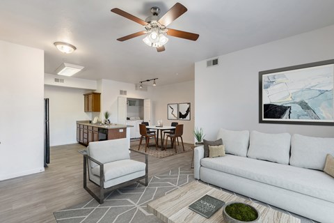A living room with a white couch, a grey armchair, a coffee table, and a ceiling fan.