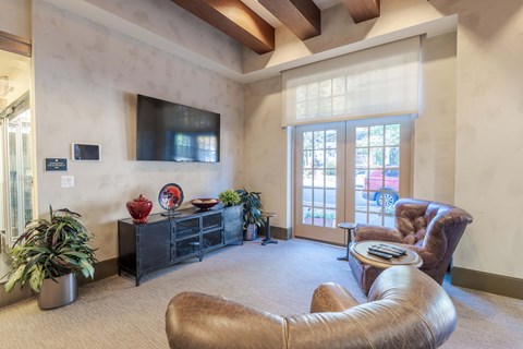 A living room with a brown leather chair and a flat screen TV mounted on the wall.