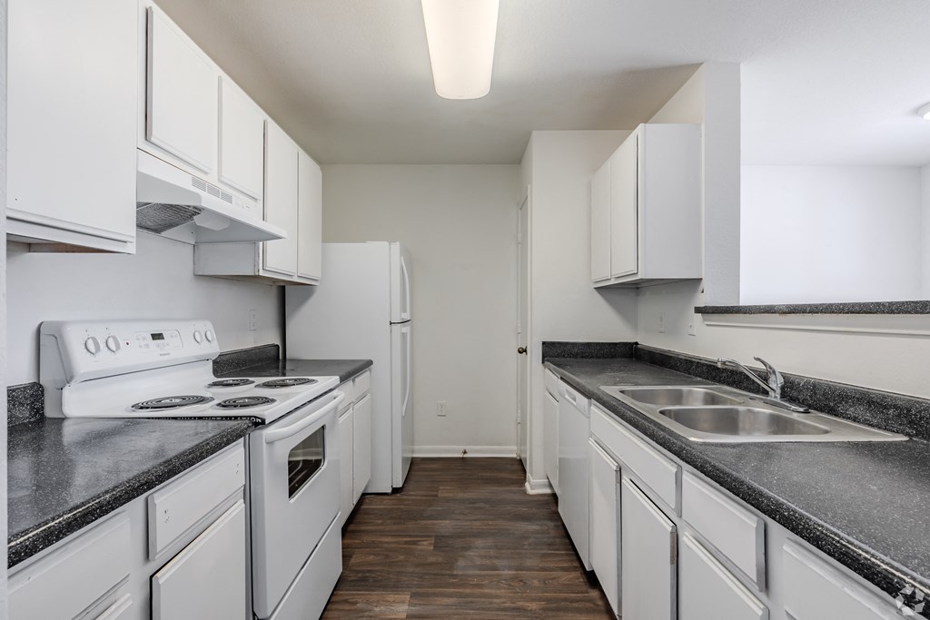 a kitchen with white cabinets and white appliances and granite counter tops at Greens at Stonecreek, Lithonia, 30038