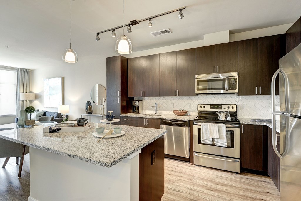 A modern kitchen with a granite countertop and stainless steel appliances.
