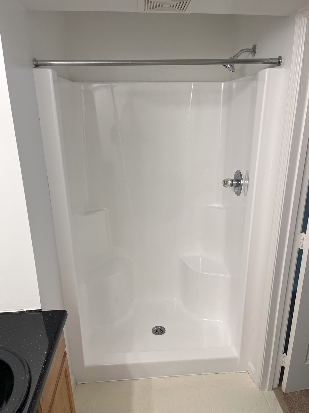 A white shower stall with a door and a drain at Shenandoah Station Apartments, Triangle, 22172