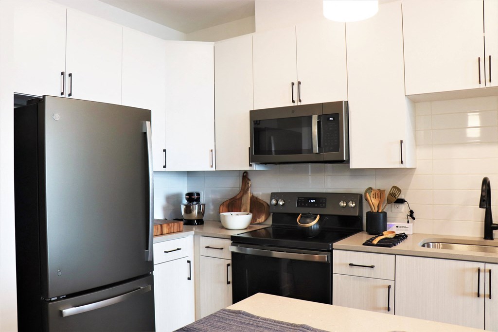 a kitchen with white cabinets and black appliances at Vyne One Loudoun, Ashburn, 20147