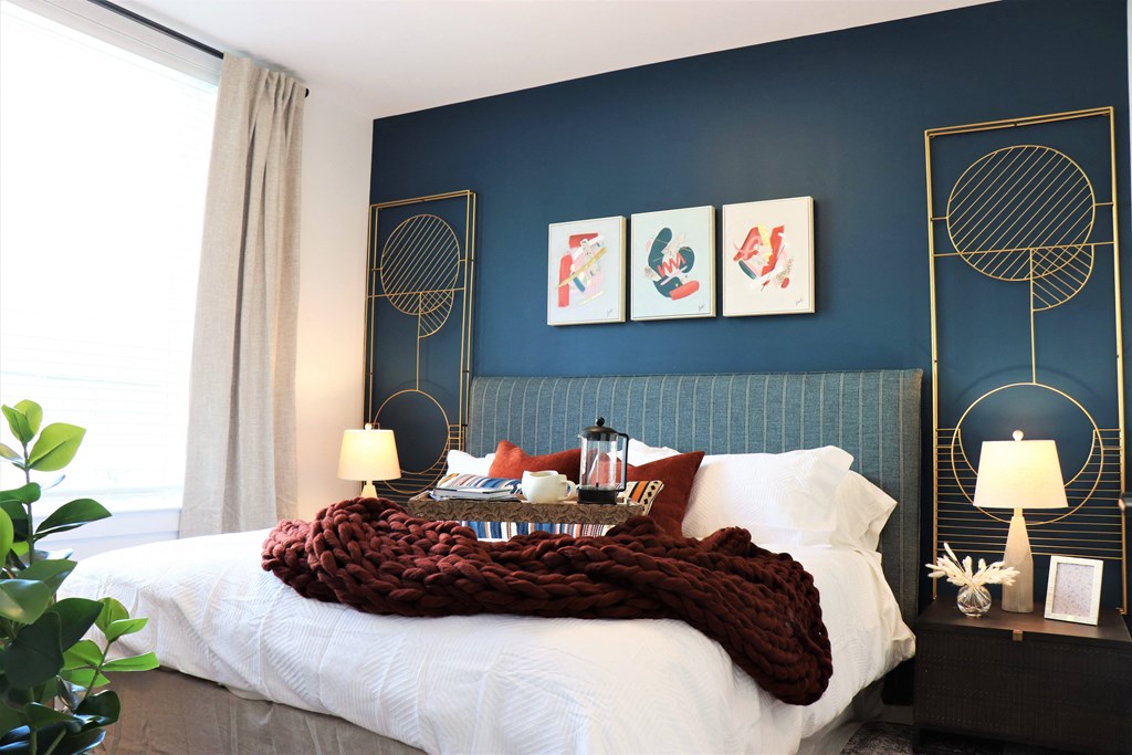 a bedroom with a blue wall and a white bed with a white comforter at Vyne One Loudoun, Ashburn, VA, 20147