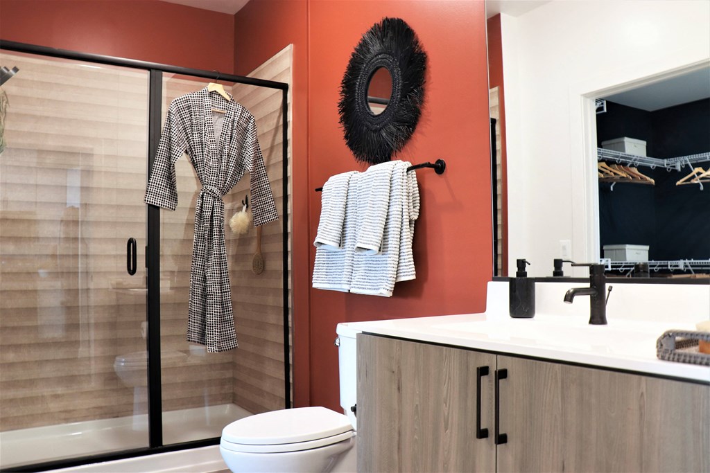 a bathroom with orange walls and a shower with a glass door at Vyne One Loudoun, Virginia