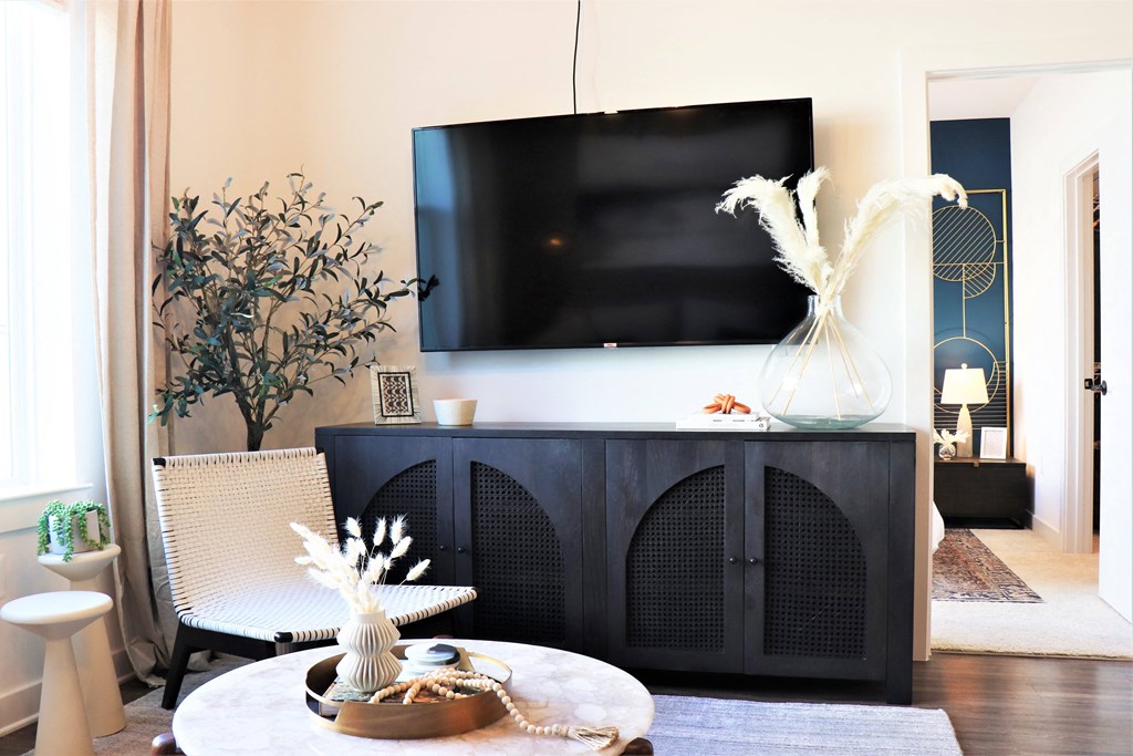 a living room with a tv on the wall and a table with a vase of flowers at Vyne One Loudoun, Ashburn, VA