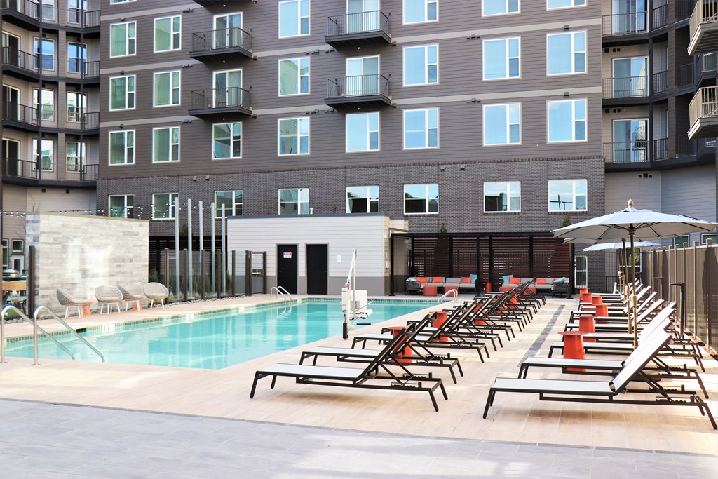 an outdoor pool with chaise lounge chairs and a building in the background at Vyne One Loudoun, Virginia, 20147