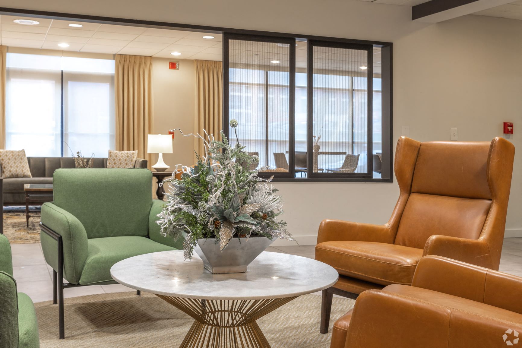 Community Clubroom a seating area with chairs and a table with a vase of flowers on top of it  at The Redwood, Baltimore, 21201