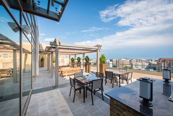 a rooftop terrace with tables and chairs and a view of the city at The Acadia at Metropolitan Park Apartments in Arlington, VA 22202