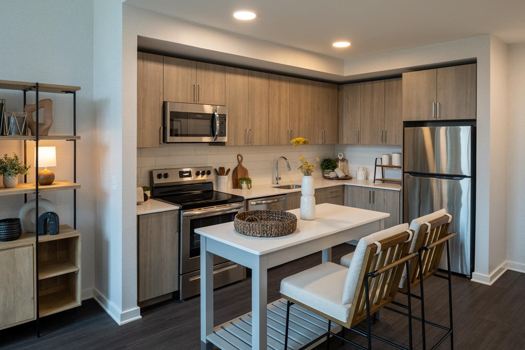 a kitchen with a white table and chairs and a stainless steel refrigerator and stove  at Brentford at The Mile, Tysons, 22102