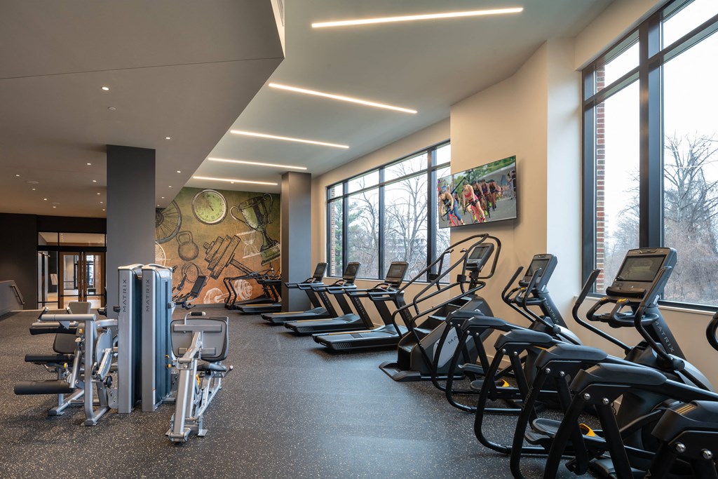 a room filled with cardio equipment and large windows at Brentford at The Mile, Virginia