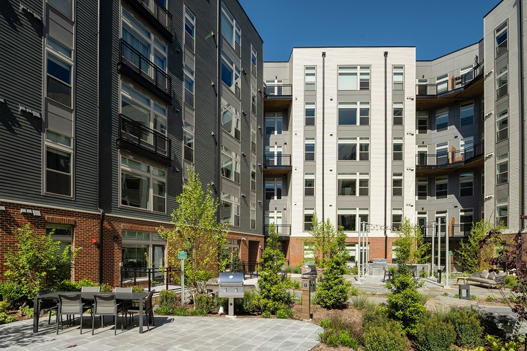 a courtyard with tables and chairs in front of a building at Brentford at The Mile, Virginia