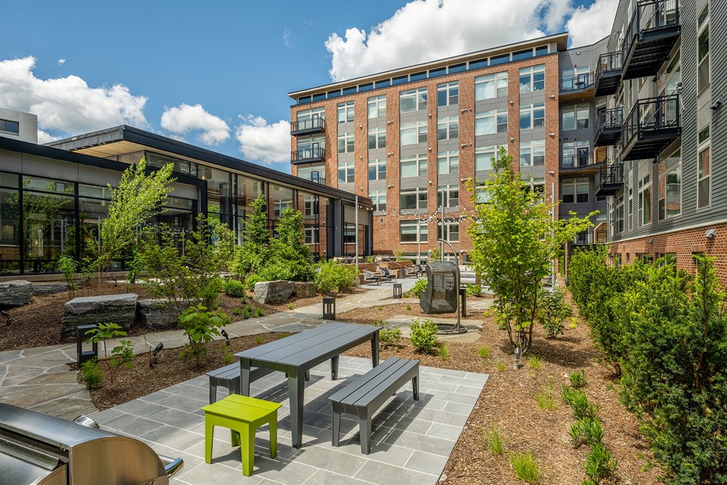 a courtyard with a picnic table and benches in front of a building at Brentford at The Mile, Virginia