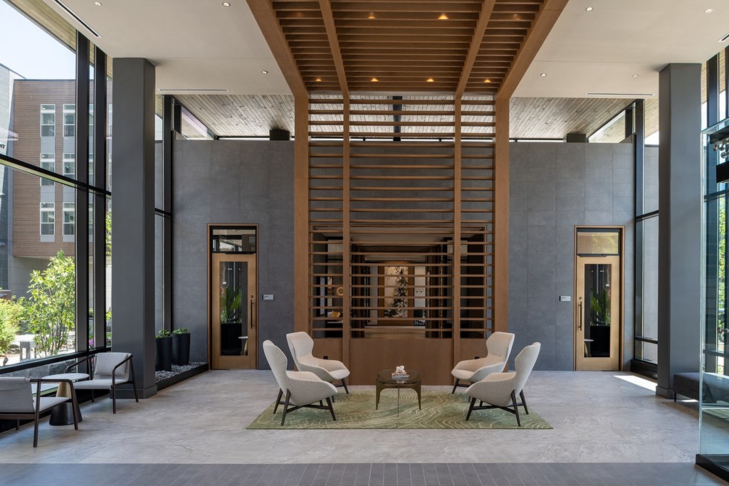 a room with a table and chairs in front of a wall of windows at Brentford at The Mile, Tysons