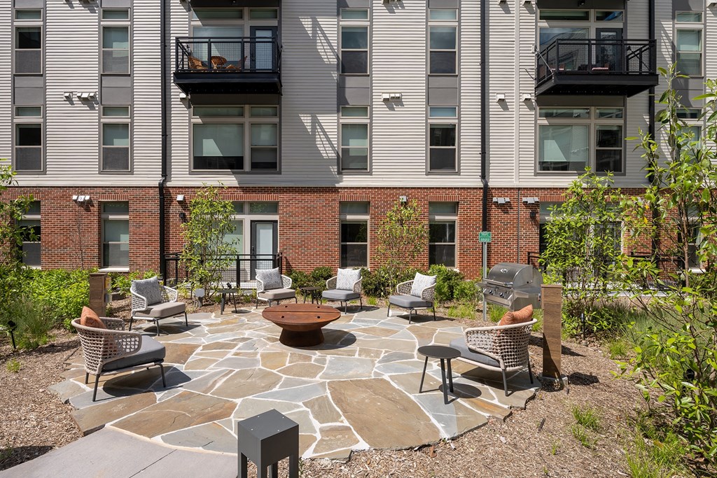 a patio with chairs and a fire pit in front of an apartment building  at Brentford at The Mile, Virginia