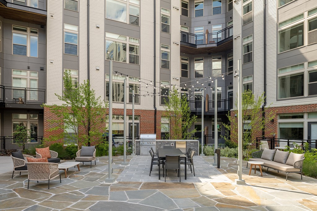 a patio with a table and chairs in front of an apartment building  at Brentford at The Mile, Tysons