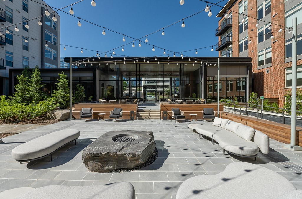 a view of the outdoor seating area with a fire pit and string lights in front of the at Brentford at The Mile, Tysons