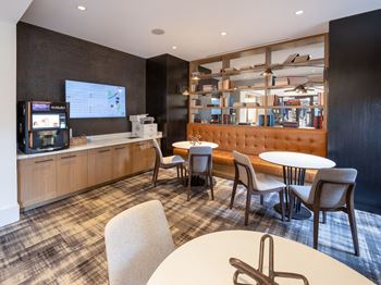 a lounge area with tables and chairs and a television at Lincoln Old Town, Alexandria, 22314