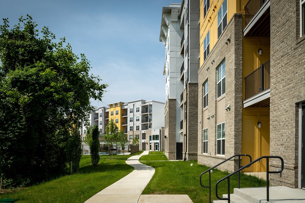 a pathway leads through a grassy area in front of an apartment building  at Woodmore Grand, Bowie