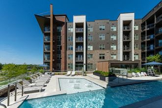 a swimming pool with lounge chairs next to an apartment building