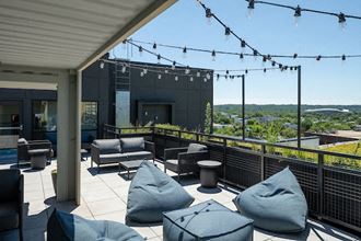 a patio with couches and chairs and lights on a roof