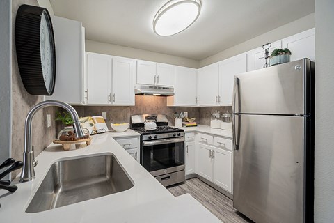 A modern kitchen with a stainless steel refrigerator and a sink with a faucet.