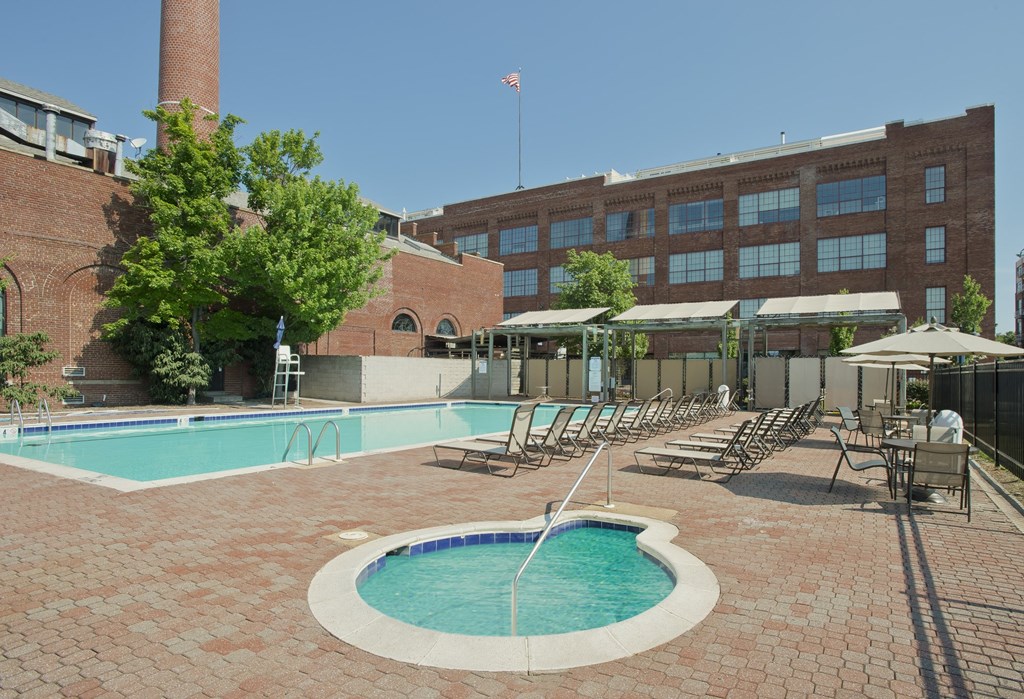 a swimming pool with chaise lounge chairs in front of a building at Tindeco Wharf, Maryland, 21224