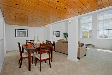 a dining room and living room with a wooden ceiling and a table and chairs