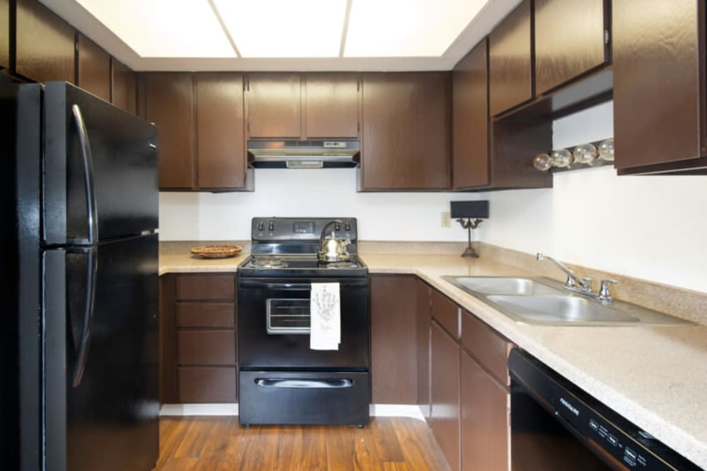 A black refrigerator is in a kitchen with brown cabinets.at Country Woods, Utah, 84401