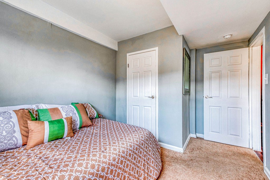A bedroom with a bed and two doors. A bedroom with a bed and two doors at Huntwood Courts Apartments, Washington DC