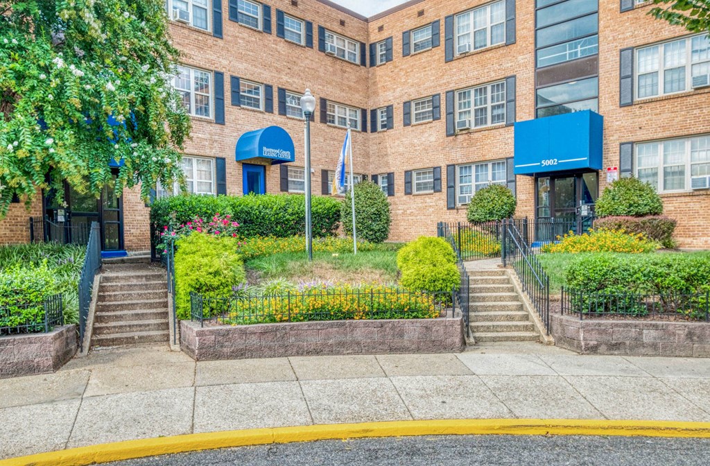 A building with a blue awning and a flag in front at Huntwood Courts Apartments, Washington, DC