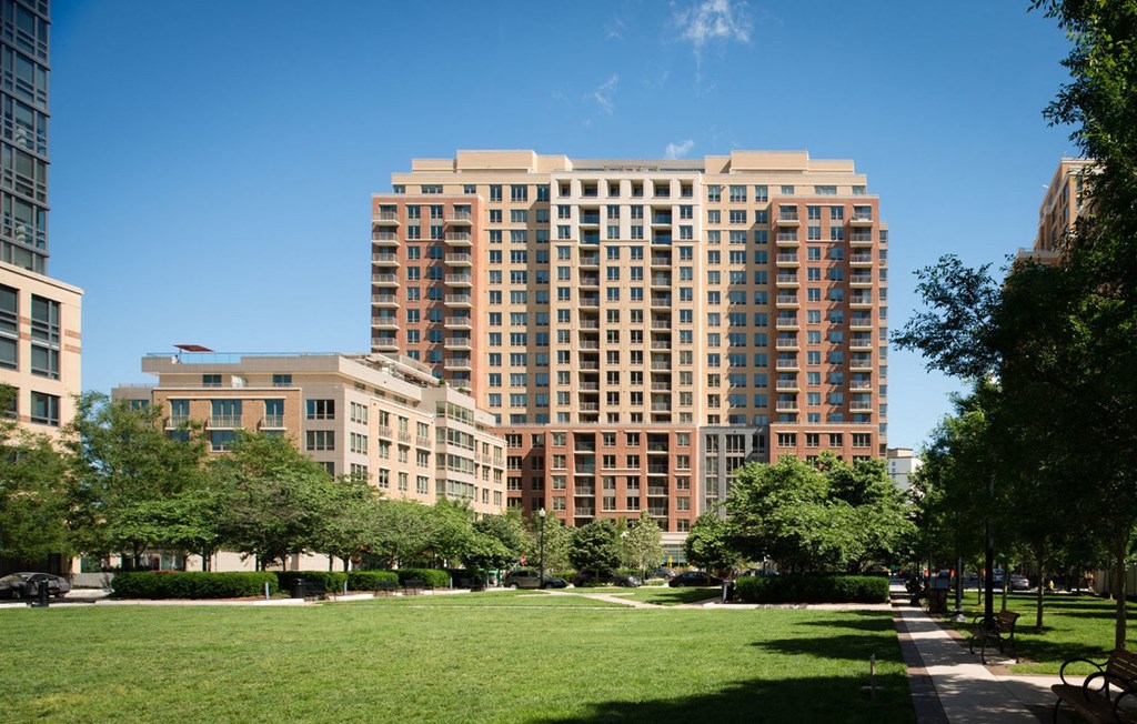 a tall building with many windows and a green park in front of it at The Acadia at Metropolitan Park, Arlington, 22202