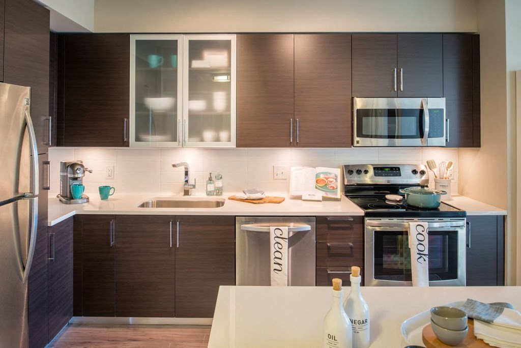 a modern kitchen with dark wood cabinets and white countertops at The Acadia at Metropolitan Park, Virginia