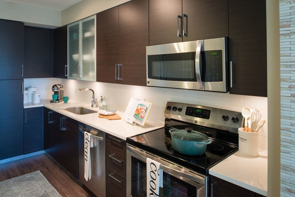 a kitchen with a stove top oven next to a sink at The Acadia at Metropolitan Park, Arlington