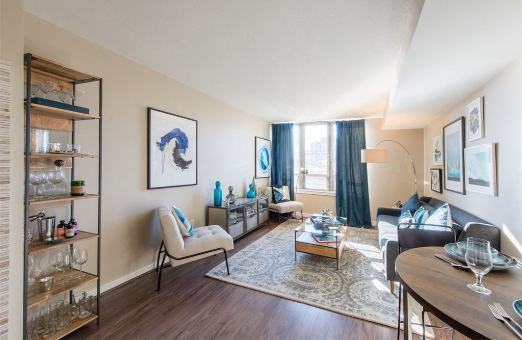 a living room with white walls and a large window with blue curtains at The Acadia at Metropolitan Park, Arlington, 22202