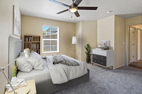 A bedroom with a bed, nightstand, and a ceiling fan. at Bluffs Apartments, Bluffdale