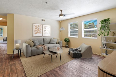 A living room with a grey couch, a small table, and a ceiling fan.