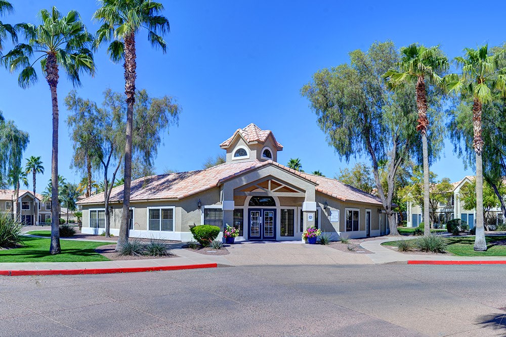 A building with a red roof and palm trees in front.at Cottonwood Crossing, Arizona  