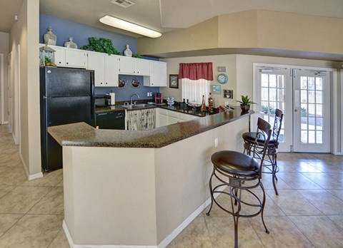 A kitchen with a black refrigerator and white cabinets.