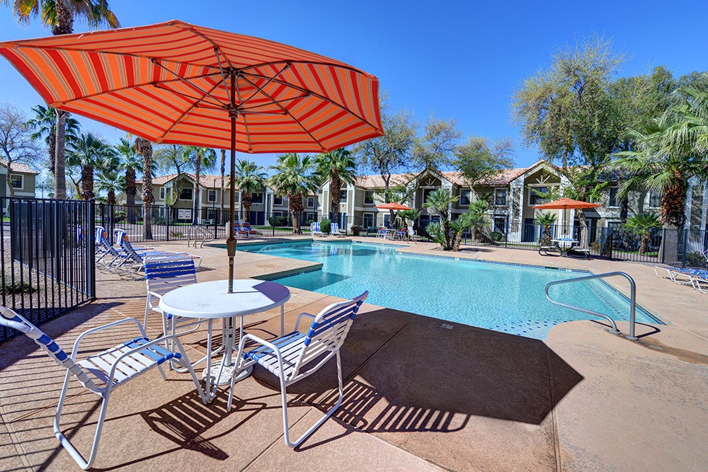 A pool area with a table and chairs under an orange umbrella.at Cottonwood Crossing, Casa Grande, 85122  