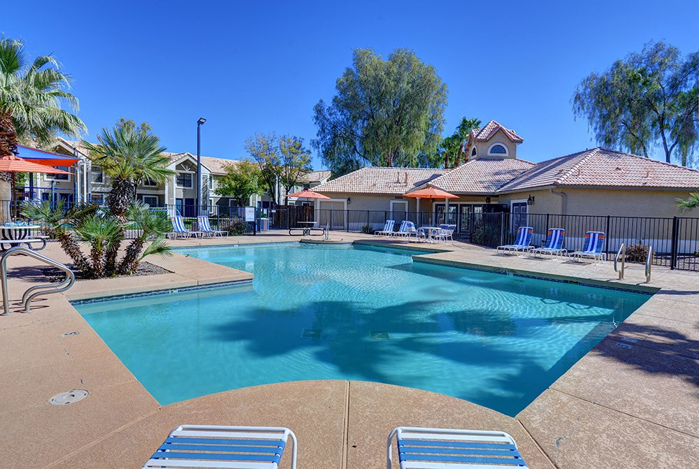 A large swimming pool surrounded by lounge chairs and palm trees.at Cottonwood Crossing, Arizona, 85122
