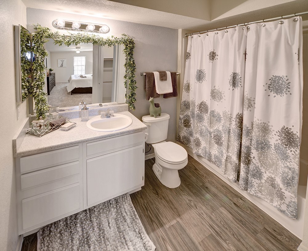 A bathroom with a white toilet, sink, and shower curtain.at Cottonwood Crossing, Casa Grande, Arizona  