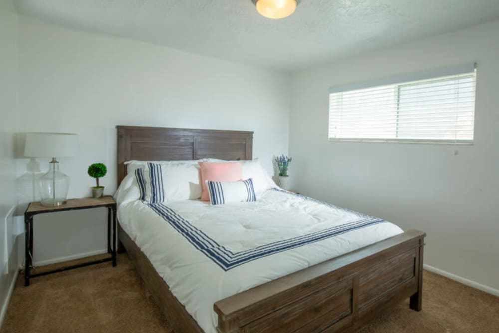 A bedroom with a bed, nightstand, and window. A bedroom with a bed, nightstand, and window.at Country Woods, Ogden Utah