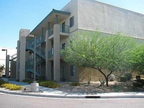 A concrete building with a tree in front at Rancho Cielo Senior Apartments, Phoenix, Arizona
