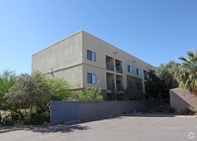 A modern building with a flat roof and a parking lot in front at Rancho Cielo Senior Apartments, Phoenix, AZ