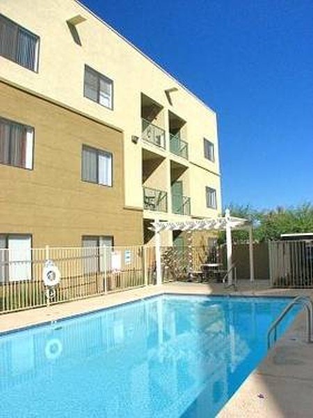 A swimming pool is in front of a tan building with a balcony at Rancho Cielo Senior Apartments, Arizona, 85009