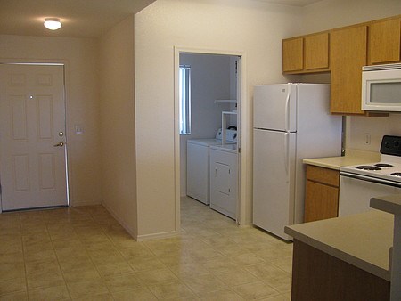 A kitchen with white appliances and wooden cabinets at Rancho Cielo Senior Apartments, Phoenix, AZ, 85009