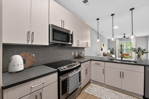 A modern kitchen with a black countertop and white cabinets.